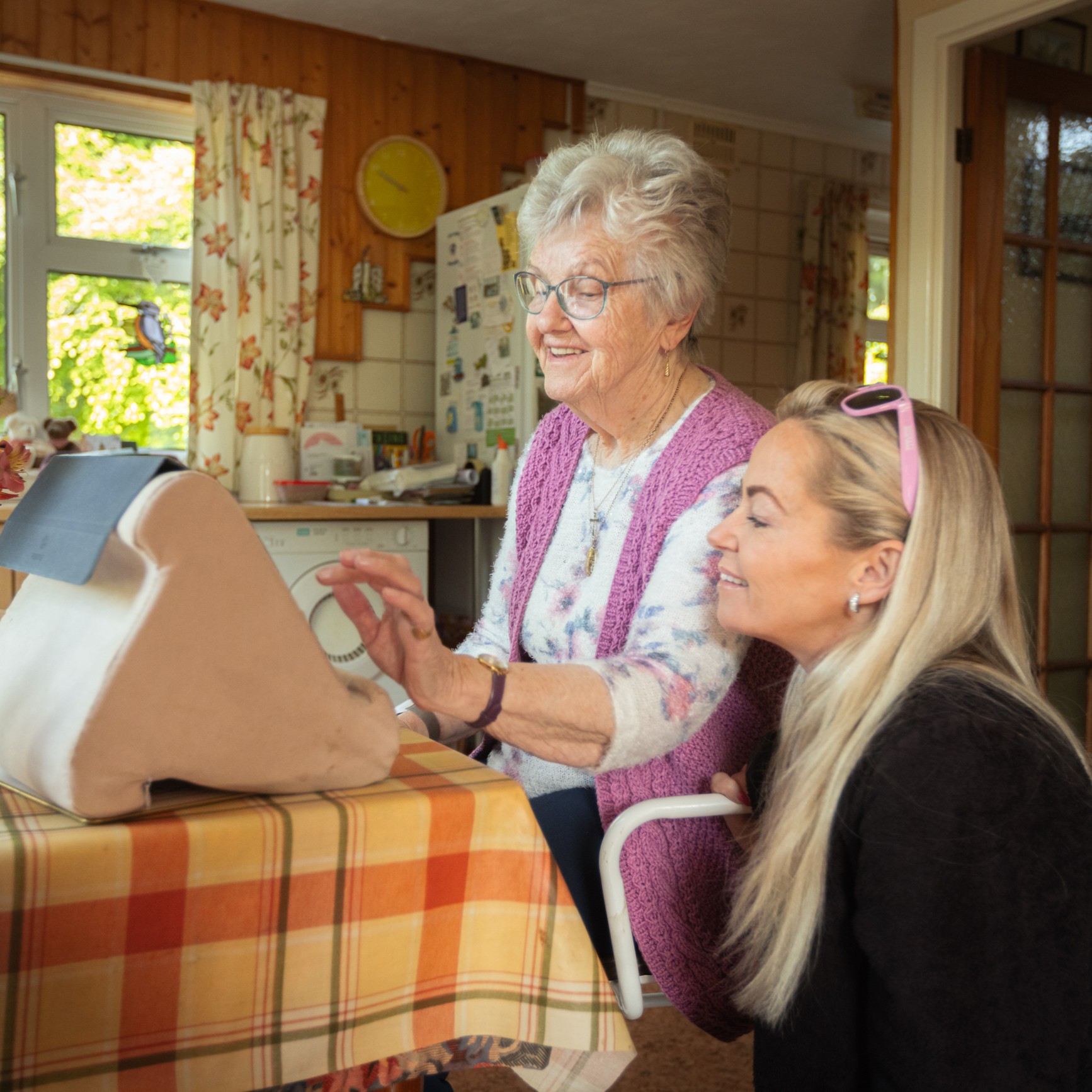 A support worker with an older woman assisting with tech