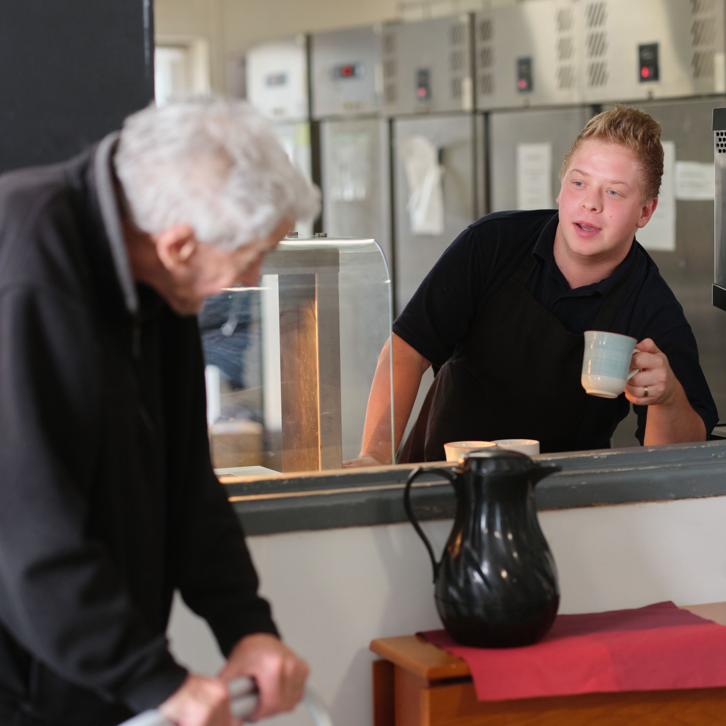 A care worker offering a resident a cup of tea