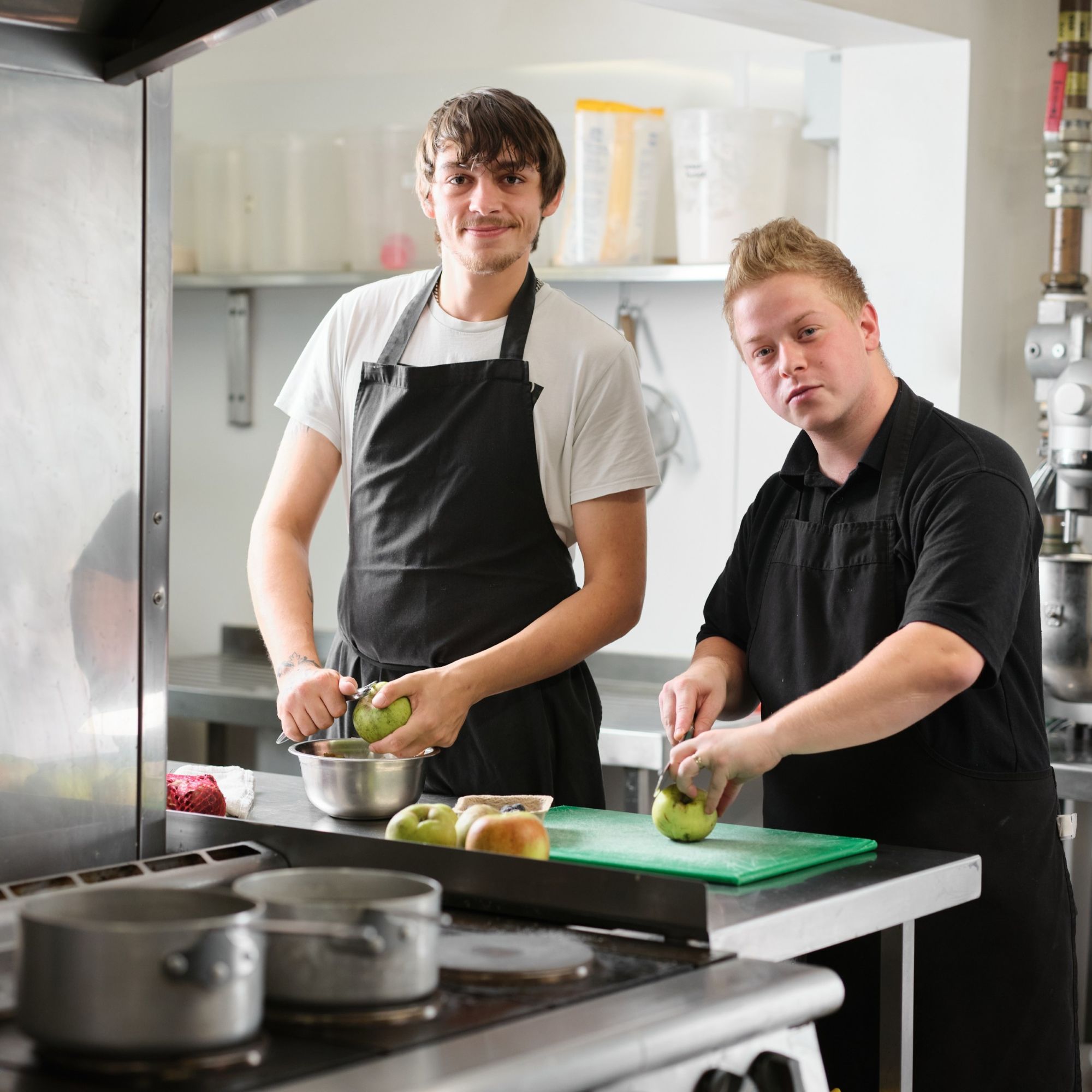 Two men peeling apples in a kitchen