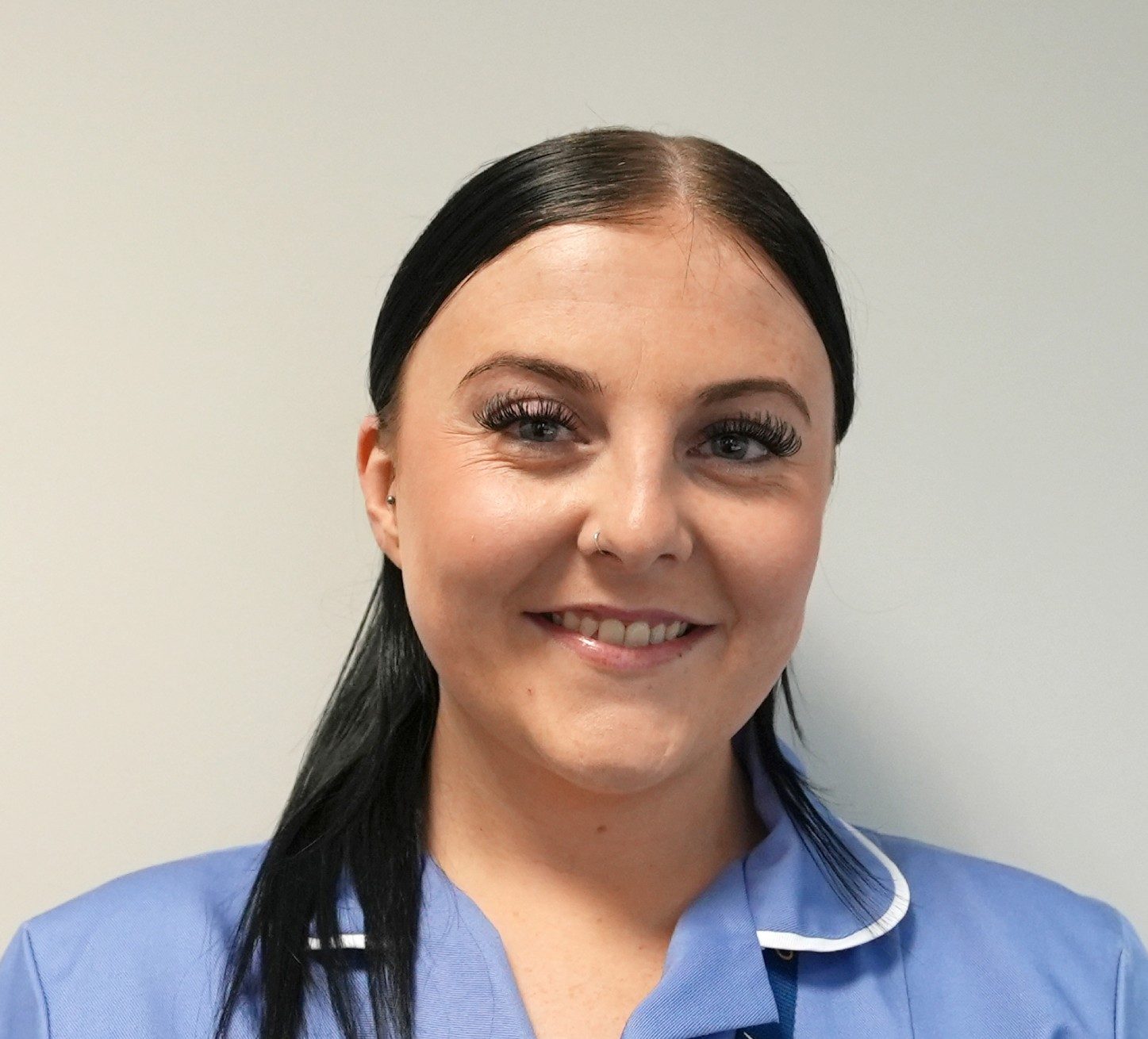 A young female home care worker in her uniform smiling at the camera